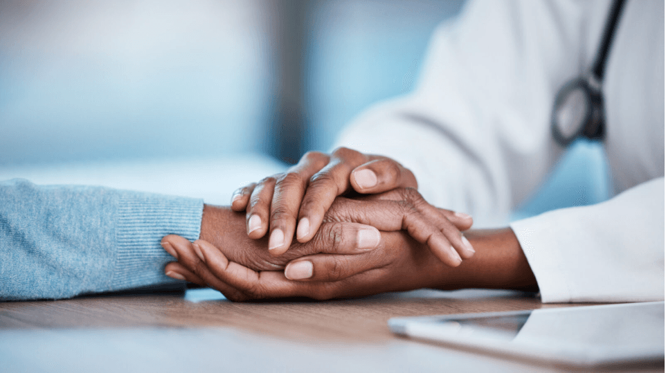 A provider offering a reassuring, compassionate hand