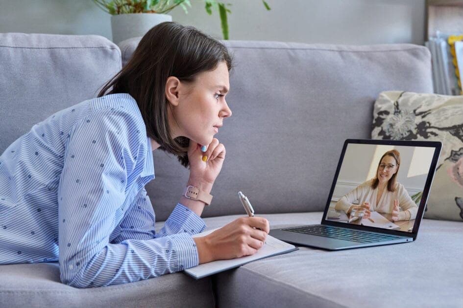 A patient taking notes while talking with a clinician over a telehealth visit